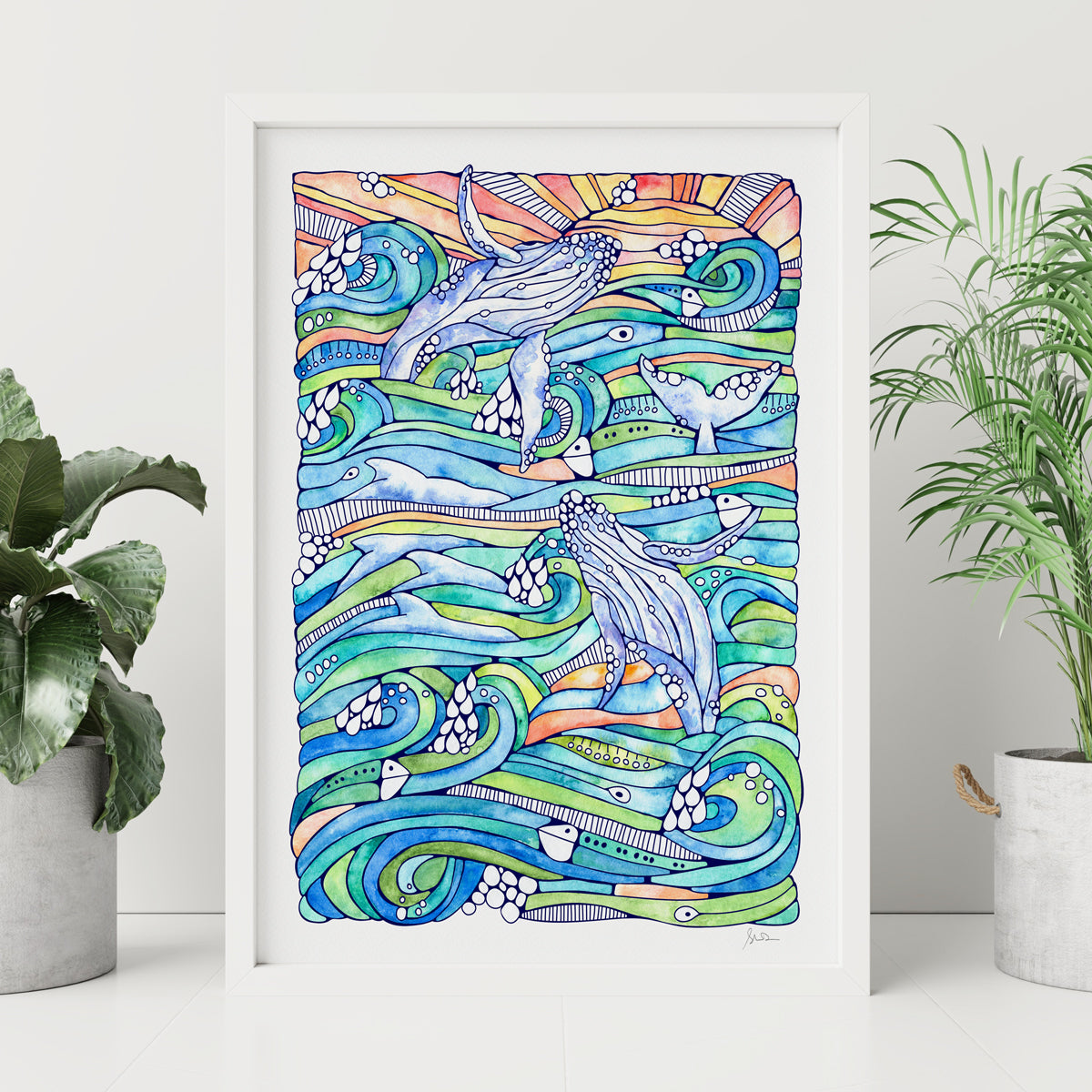 Colorful artwork of whales and waves in a frame on a white wall with plants.